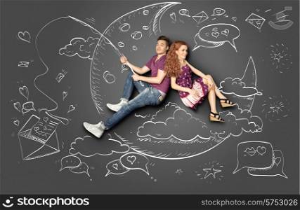 Happy valentines love story concept of a romantic couple fishing on a moon with a paper letter on a hook against chalk drawings background.