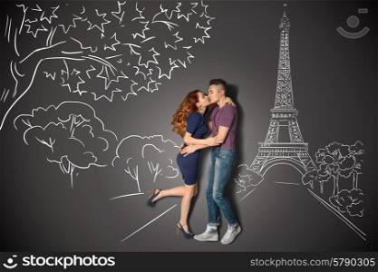 Happy valentines love story concept of a romantic couple in Paris kissing under the Eiffel Tower against chalk drawings background.