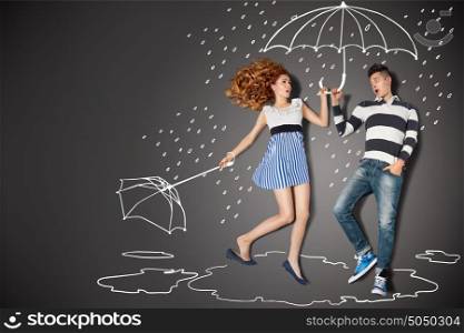 Happy valentines love story concept of a romantic couple in the rain against chalk drawings background.