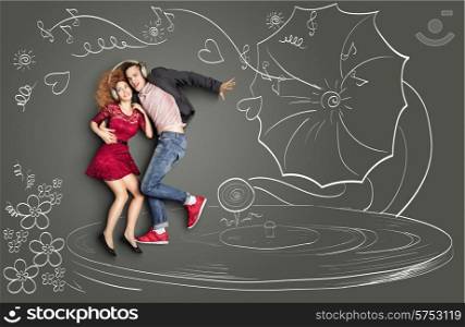 Happy valentines love story concept of a romantic couple sharing headphones, listening to the music and dancing on a gramophone, against chalk drawings background.