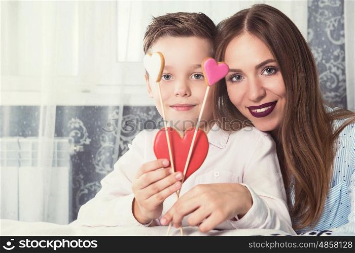 Happy Valentines or mother day. Happy Valentines Day or Mother day. Young boy spend time with his mum and celebrate with gingerbread heart cookies on a stick.