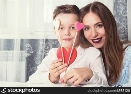 Happy Valentines or mother day. Happy Valentines Day or Mother day. Young boy spend time with his mum and celebrate with gingerbread heart cookies on a stick.