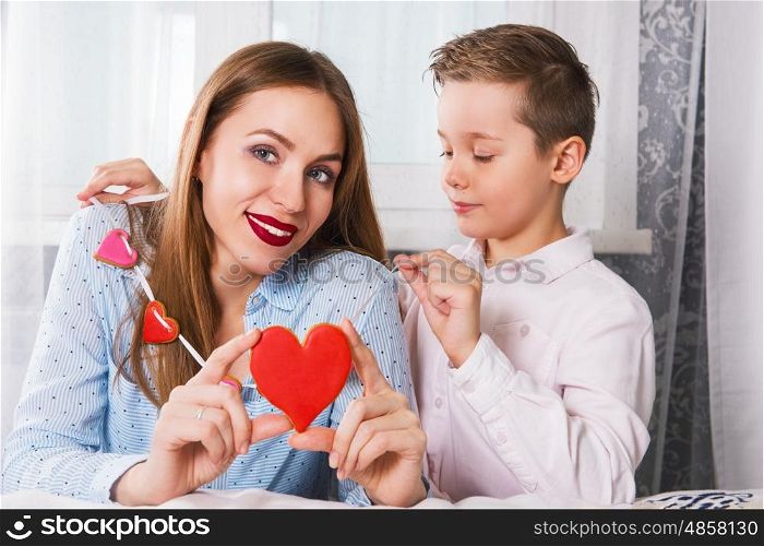 Happy Valentines or mother day. Happy Valentines Day or Mother day. Young boy and mum celebrate with gingerbread heart cookies on a stick.