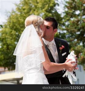 Happy wedding couple, they are holding doves in their hands and want to let them fly free as a symbol of love, and they are kissing each other