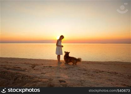 happy weekend by the sea - little girl is walking with a dog by the sea at sunset. Ukrainian landscape at the Sea of Azov, Ukraine