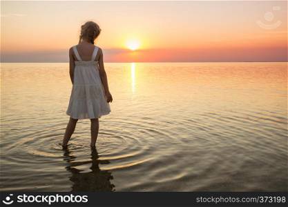 happy weekend by the sea - little girl looks at the sunset at the sea. Ukrainian landscape at the Sea of Azov, Ukraine