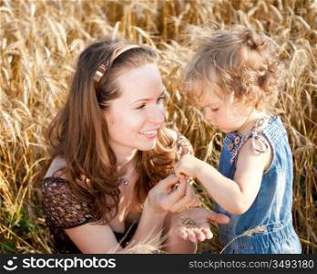 Happy woman and child eating bread in spring wheat field