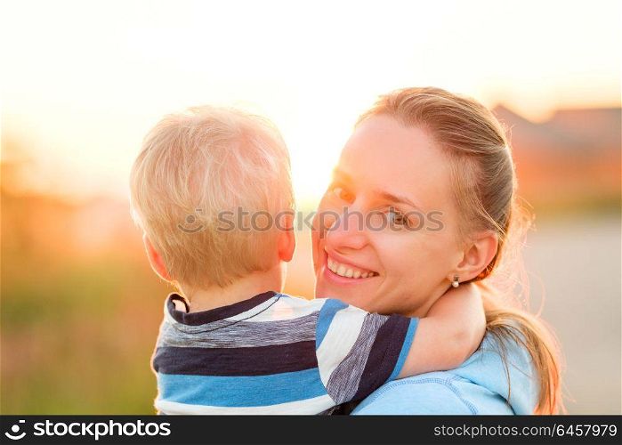 Happy woman and child having fun outdoors. Family lifestyle rural scene of mother and son in sunset sunlight.