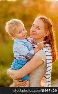 Happy woman and child having fun outdoors. Family lifestyle rural scene of mother and son in sunset sunlight.