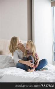 Happy woman and daughter looking at each other in bedroom