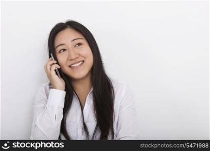 Happy woman answering cell phone against white background