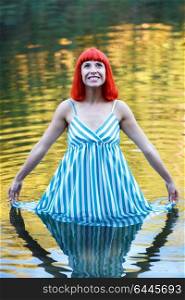 Happy woman bathing in a beautiful river wearing a blue dress