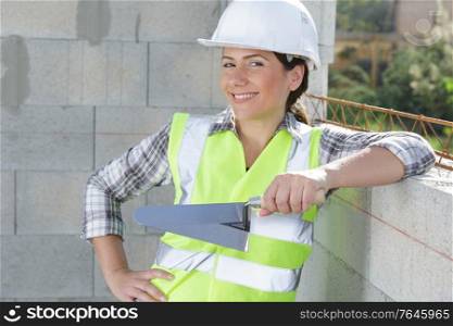 happy woman builder worker plastering a wall
