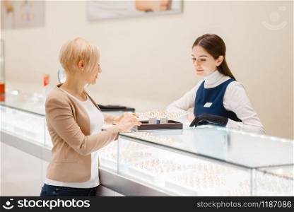 Happy woman choosing wedding rings in jewelry store. Female person buying gold decoration in jewellery shop. Woman choosing wedding rings in jewelry store