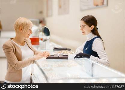 Happy woman choosing wedding rings in jewelry store. Female person buying gold decoration in jewellery shop