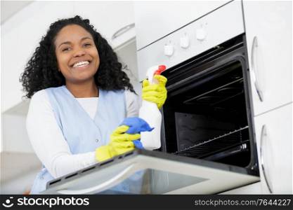 happy woman cleaning oven at home kitchen