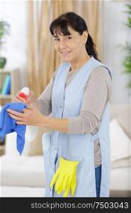 happy woman cleaning with a spray detergent