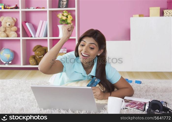 Happy woman clenching fist while shopping online at home