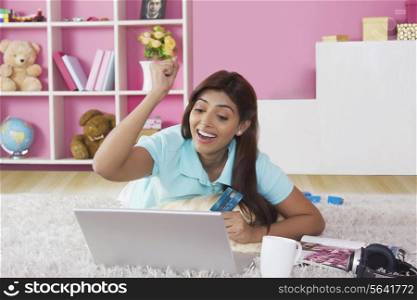 Happy woman clenching fist while shopping online at home