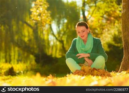 Happy woman collecting autumn leaves in park to make beautiful decorative autumnal bouquet. Happy woman collecting leaves in park
