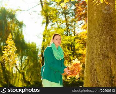Happy woman collecting autumn leaves in park to make beautiful decorative autumnal bouquet. Happy woman collecting leaves in park