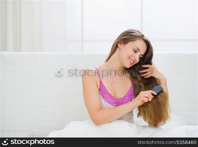 Happy woman combing beautiful long hair
