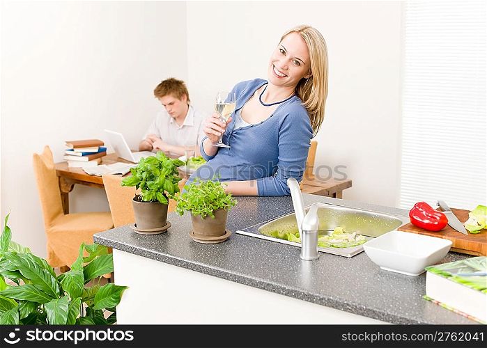 Happy woman cook enjoy white wine in kitchen, man in background