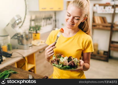 Happy woman cooking salad on the kitchen, healthy bio food preparing. Vegetarian diet, fresh vegetables and fruits on wooden table. Happy woman cooking salad, bio food preparing