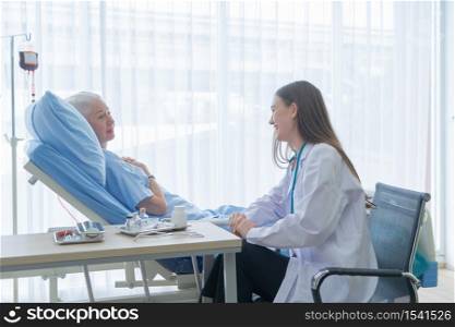 Happy woman doctor talking encourage to sick old female senior elderly patient lying in bed in hospital ward room in medical and healthcare treatment concept. Caucasian white people.