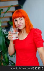 Happy woman drinking a glass of water at home