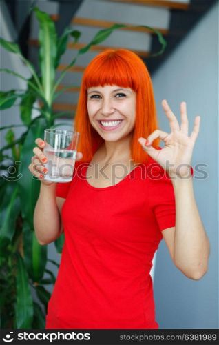 Happy woman drinking a glass of water at home