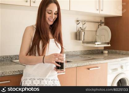 Happy woman drinking coffee in the kitchen