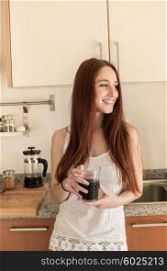 Happy woman drinking coffee in the kitchen