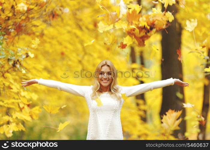 Happy woman drop up leaves in autumn park