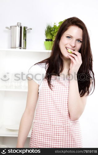 happy woman eating cucumber. happy woman in a kitchen eating cucumber