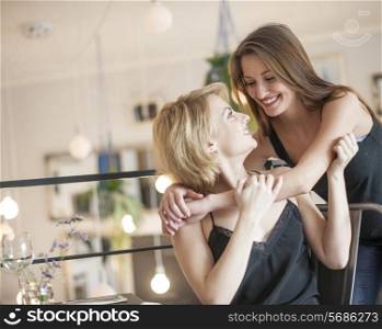 Happy woman embracing female friend in cafe