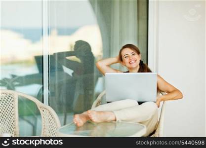 Happy woman enjoying free time with laptop on terrace