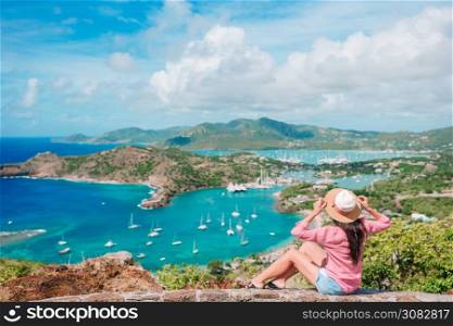 Happy woman enjoying the view of picturesque English Harbour at Antigua. View of paradise bay at tropical island in the Caribbean Sea. View of English Harbor from Shirley Heights, Antigua, paradise bay at tropical island in the Caribbean Sea