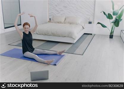Happy woman exercising body ballet keeping hands up. Distance personal training in front of camera. Concept of e-learning and home classes. Sport online while quarantine.. Woman exercising body ballet keeping hands up. Distance personal training in front of camera.