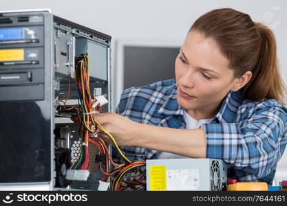 happy woman fixing computer at desk at work