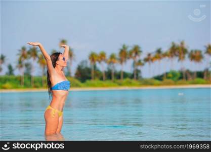 Happy woman have fun on the beach in shallow water. Young fashion woman in green dress on the beach