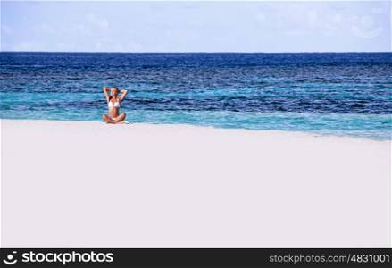 Happy woman having fun on the beach, sitting on seashore and tanning on bright sunlight, enjoying summer vacation, freedom concept