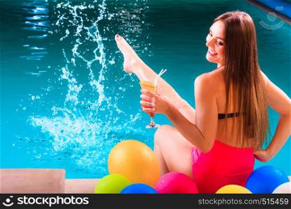 Happy woman having fun with balloons and cocktail drink alcohol splashing water. Pretty attractive girl relaxing at swimming pool edge poolside.. Happy woman with balloons and cocktail at poolside