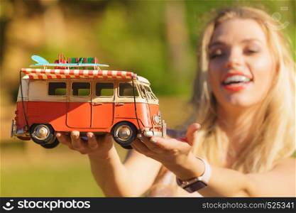 Happy woman having idea of traveling, holding hippie camper trailer decorative object model. Vehicle, summer vacations concept.. Woman holding hippie van object model