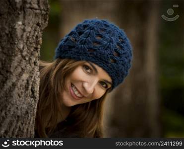 Happy woman hiding behind a tree in a beautiful autumn day