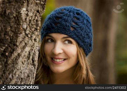 Happy woman hiding behind a tree in a beautiful autumn day