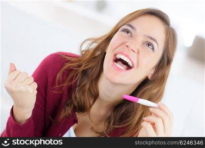 Happy woman holding a pregnancy test
