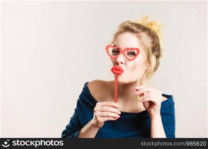 Happy woman holding fake lips and eyeglasses on stick having fun. Photo and carnival funny accessories concept.. Happy woman holding fake lips and eyeglasses on stick