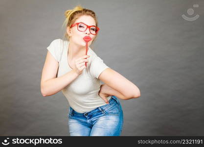 Happy woman holding fake lips on stick having fun. Photo and carnival funny accessories concept.. Happy woman holding fake lips on stick