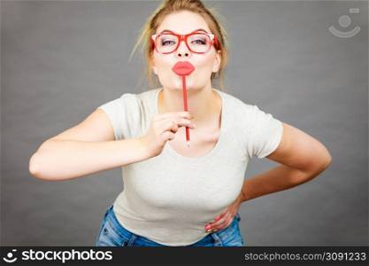 Happy woman holding fake lips on stick having fun. Photo and carnival funny accessories concept.. Happy woman holding fake lips on stick